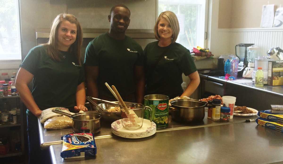 Volunteers smiling in front of baking ingredients