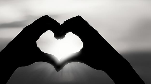 black and white image of two hands making a heart