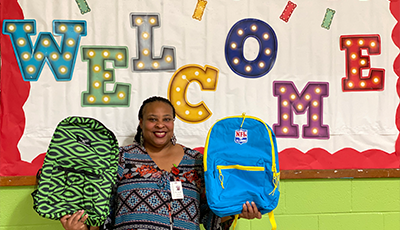 principal Natasha Jones from WB Goodwin Elementary holding two backpacks