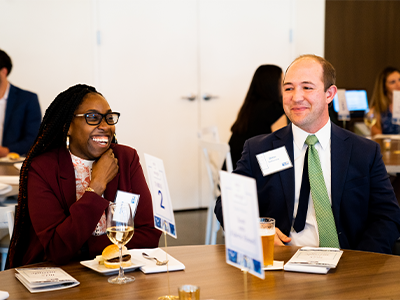 A male and female sharing a laugh while they sit at a table with drinks