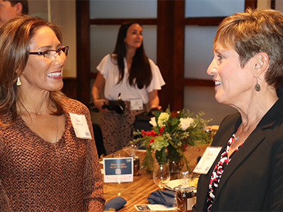 Two women with name tags on exchanging smiles to one another