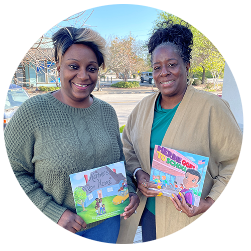 2 AALC members holding books smiling at camera