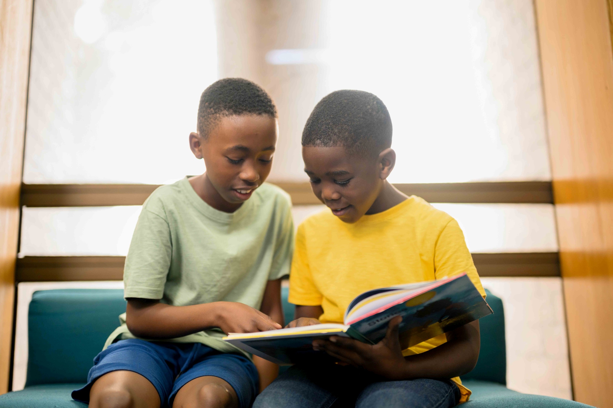 Two young boys reading a book in a building