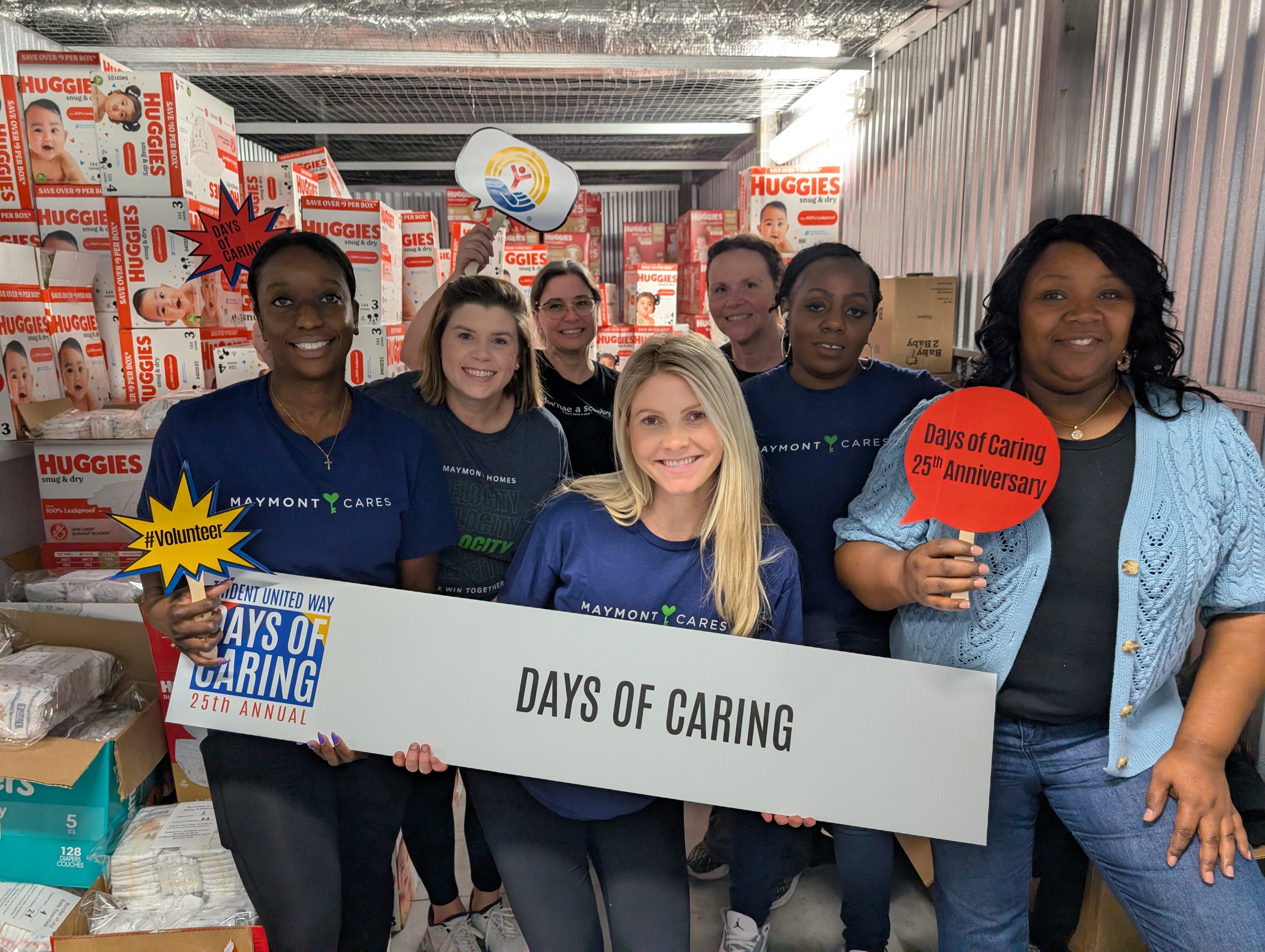 A group of Days of Caring Volunteers pose with a sign.