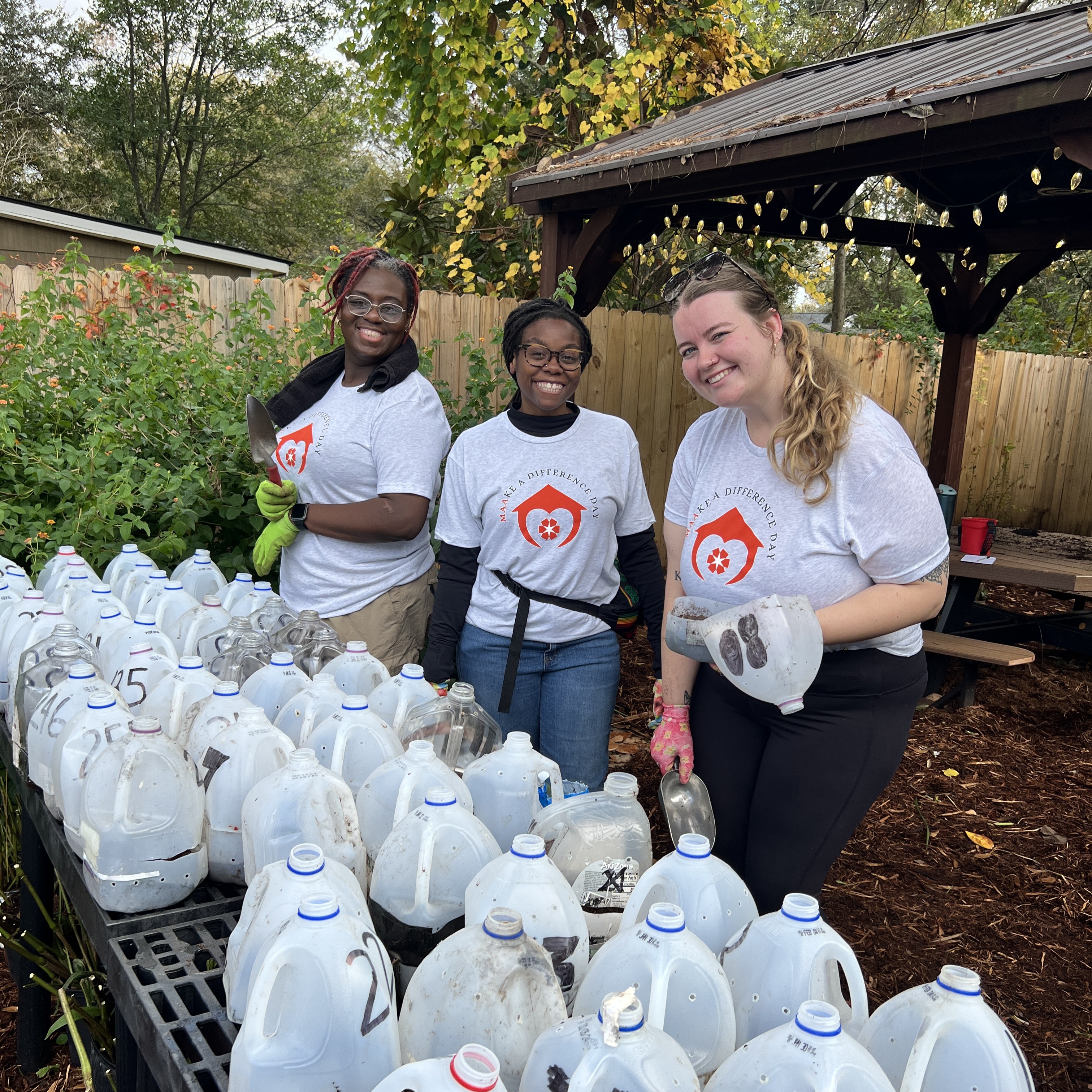 3 volunteers smile while gardening. 