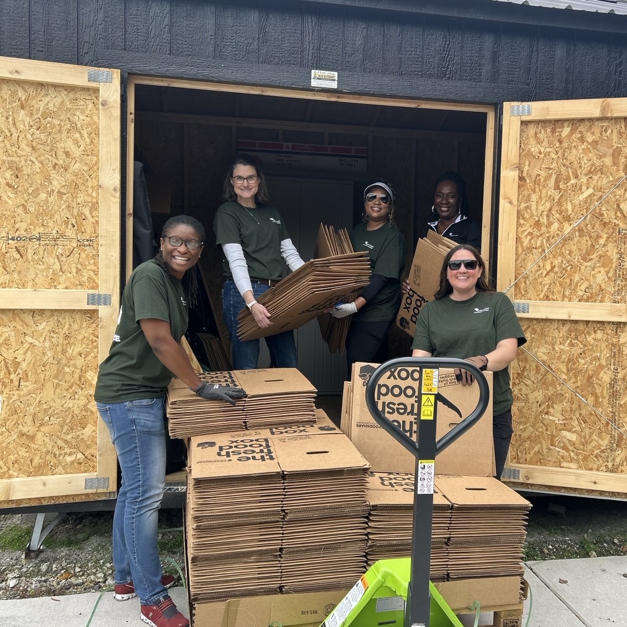 A group of Santee Cooper employees smile with cardboard boxes while volunteering.