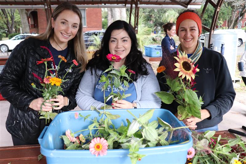 A group of Volunteers smile with flowers.