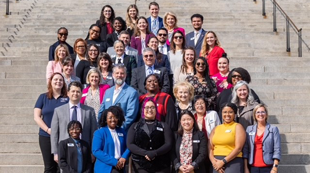 Individuals from United Ways across South Carolina standing on the steps of the SC State House. They wearing business professional clothing and smiling at the camera.