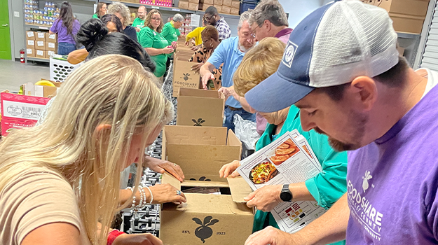 A group of individuals packing boxes assembly line style at foodshare berkeley county