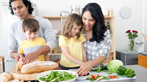 Family of four cooking a healthy meal in a well-lit kitchen