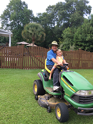 Brad Davis on a John Deer tractor with hid granddaughter 