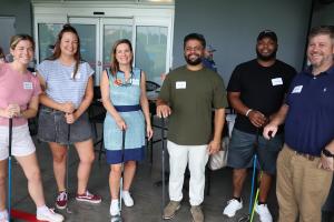 6 TUW team members standing with golf clubs posing for the camera at Top Golf