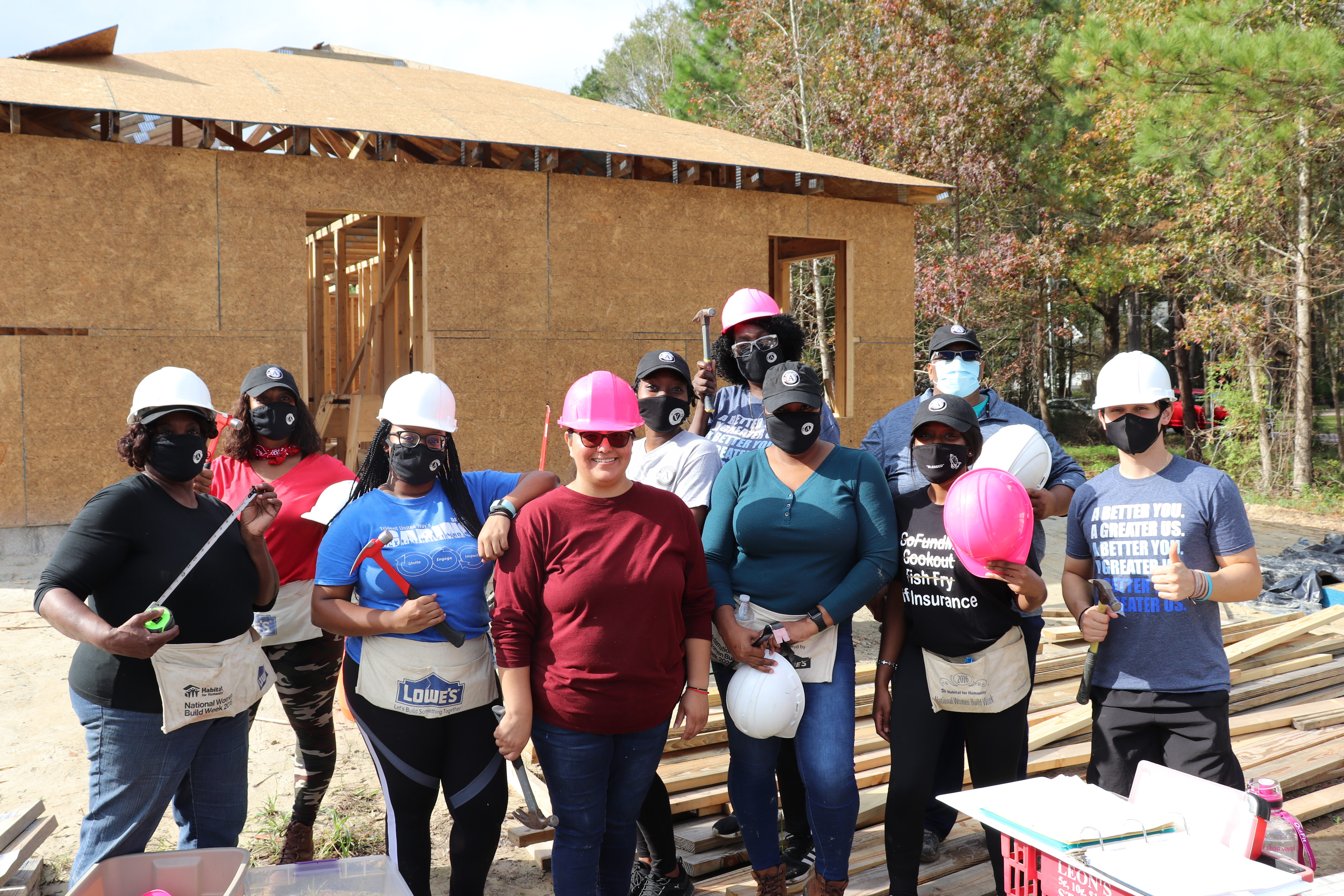 AmeriCorps members wearing hard hats and holding tools at Habitat Build