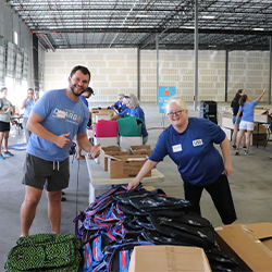 Volunteers packing backpacks with donated school supplies at UPS facility