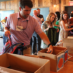 YLU member packing a backpack with donated school supplies at Firefly Distillery