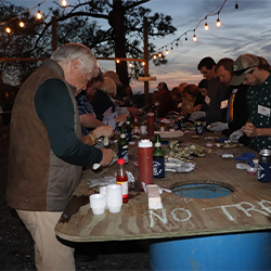 Photo of a group on individuals shucking oysters at Bowens Island during the Trident United Way Palmetto Society oyster roast