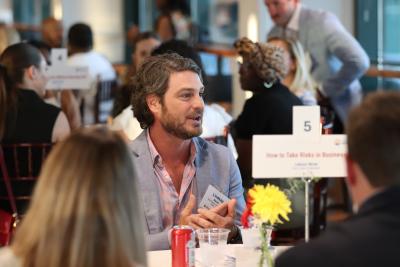 Photo from Cocktails & Conversations, a man is in center frame talking and there are people around him.