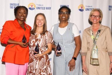 Women United Awards winners and keynote speaker in front of step and repeat