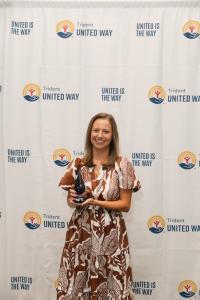 Kathleen Stevens, Hands on Hero of the Year, posting with award in front of step and repeat