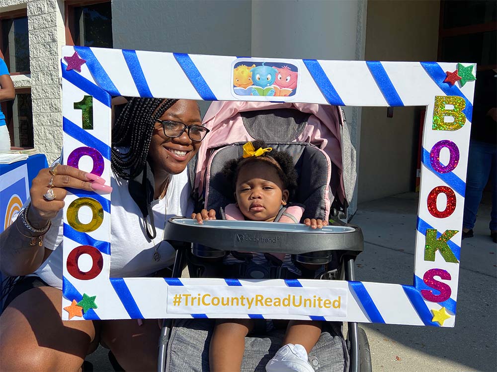 Women and baby in stroller holding sign