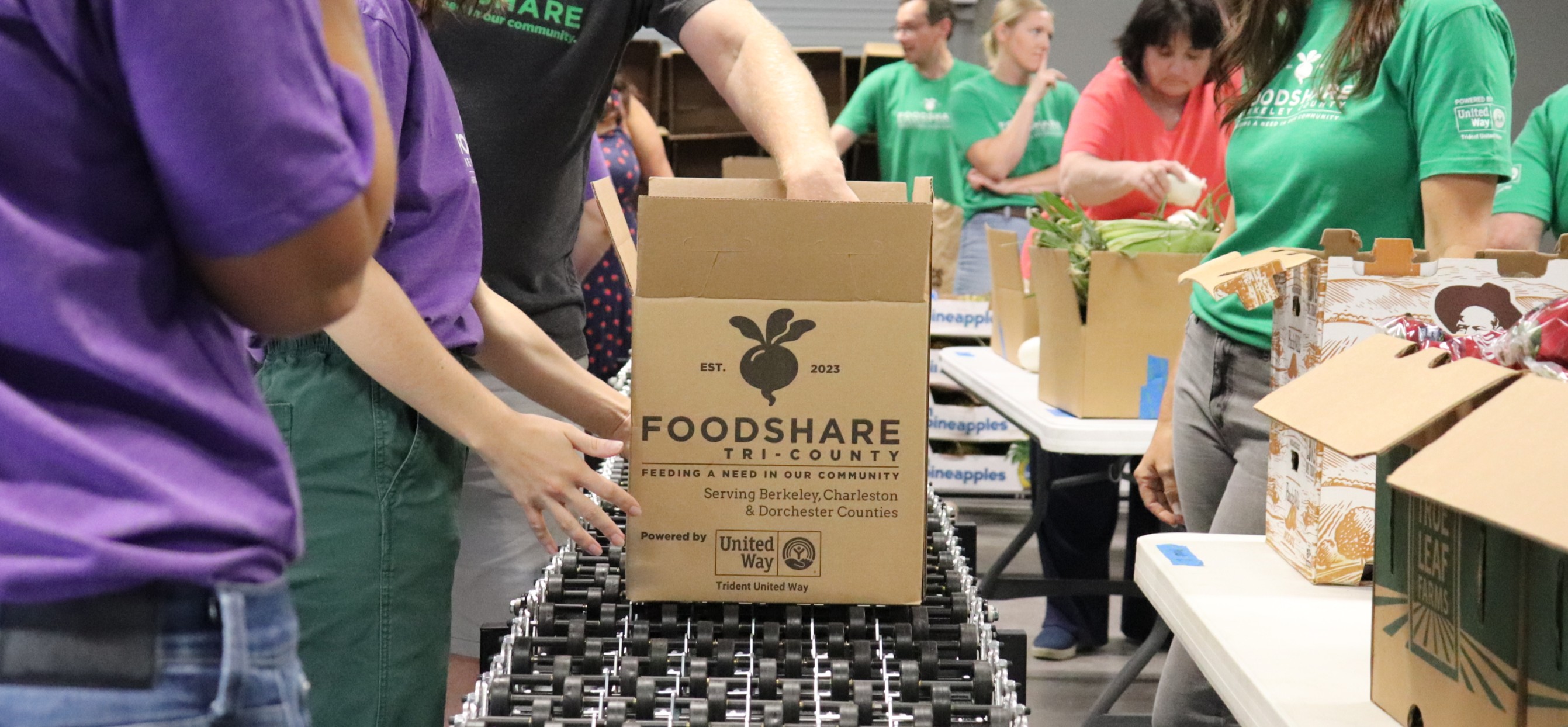 A FoodShare Tri-County box being packed by volunteers in FoodShare t-shirts.