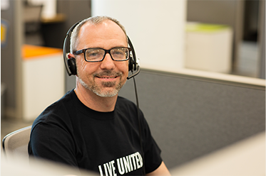 211 representative wearing a phone headset and a LIVE UNITED shirt