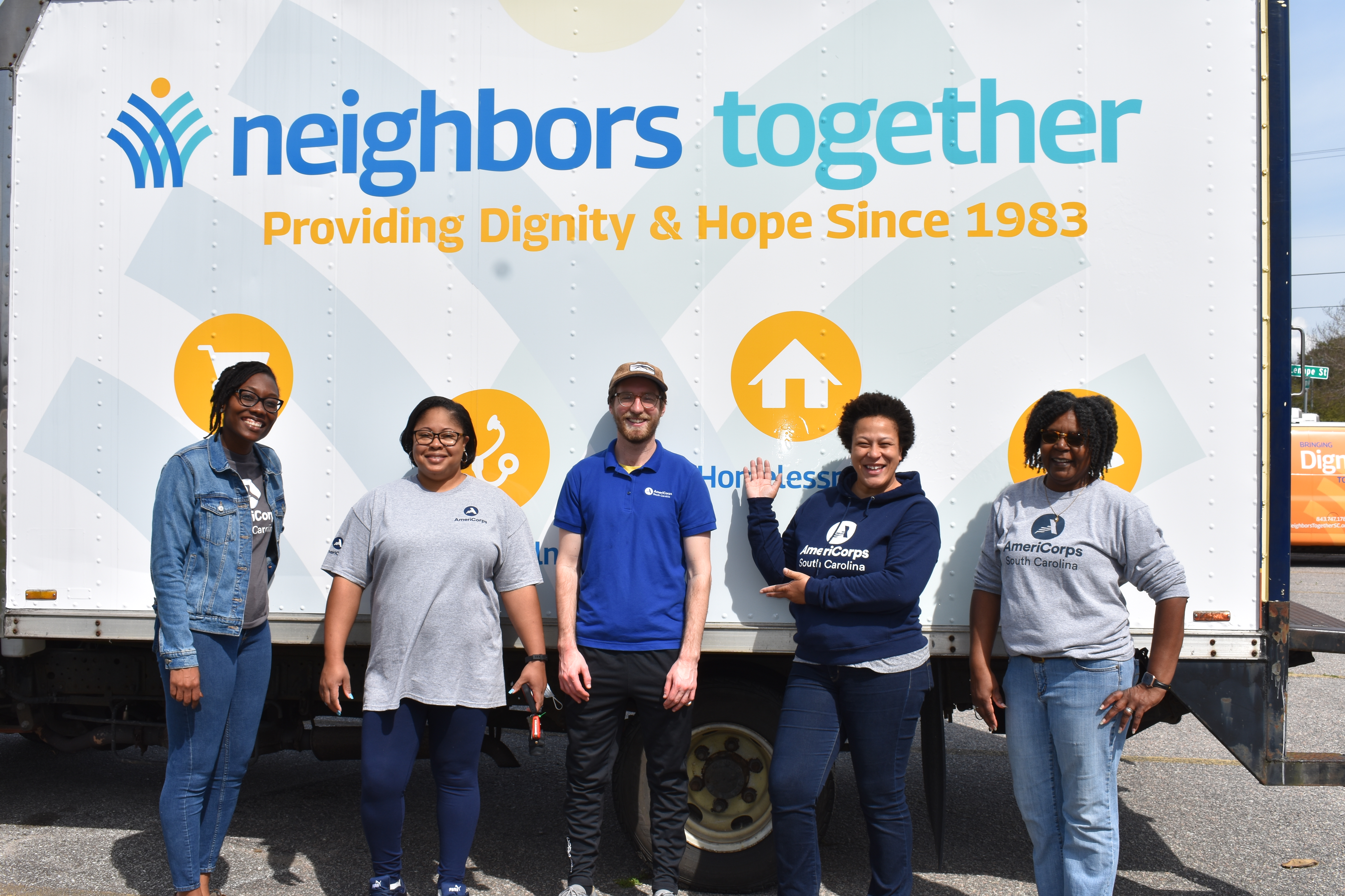 Five AmeriCorps members posing for photo in front of truck that has "Neighbors Together" written on it