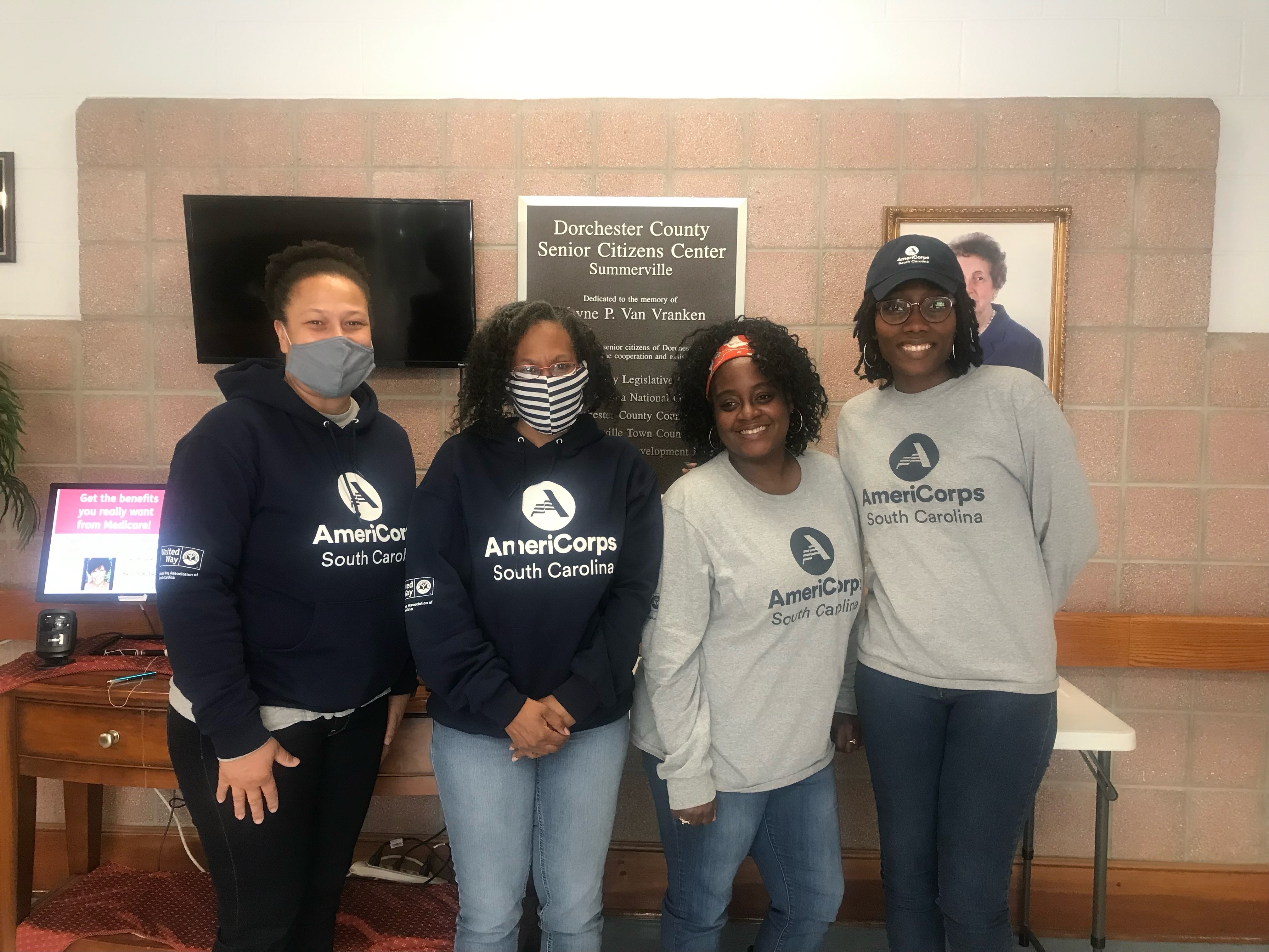 Four AmeriCorps members posing for photo wearing shirts that have AmeriCorps logo on it