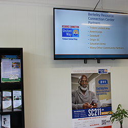 Photo of a television showing agencies inside of Berkeley resource connection center and cards and a poster detailing ways to receive assistance