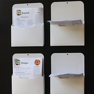 closer photo of four manilla folders, one that contains nutritional information on brocolli and one that contains nutritional information on oranges