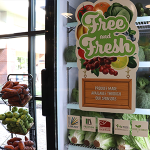 A photo of a free and fresh fridge filled with fresh produce and a three tiered stand with three baskets of fresh produce