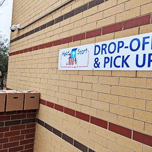 Sign on the outside of a school that says Drop off & Pic Up