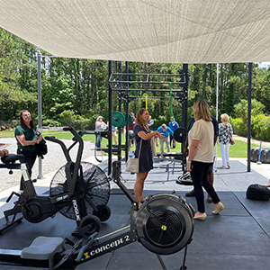 Several individuals walking around a large outdoor space that contains gym equipment