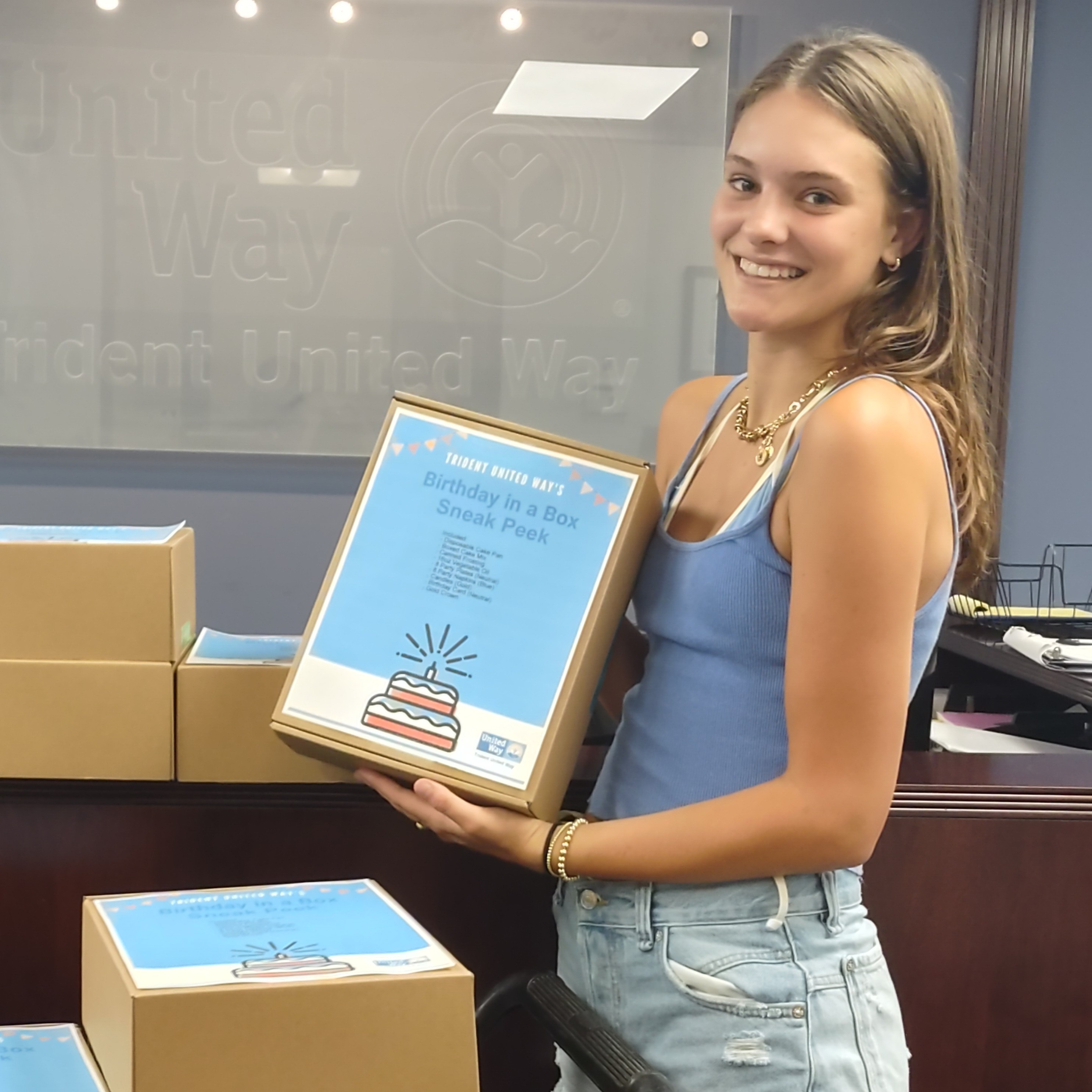A volunteer holds a birthday in a box she assembled for kids in need.