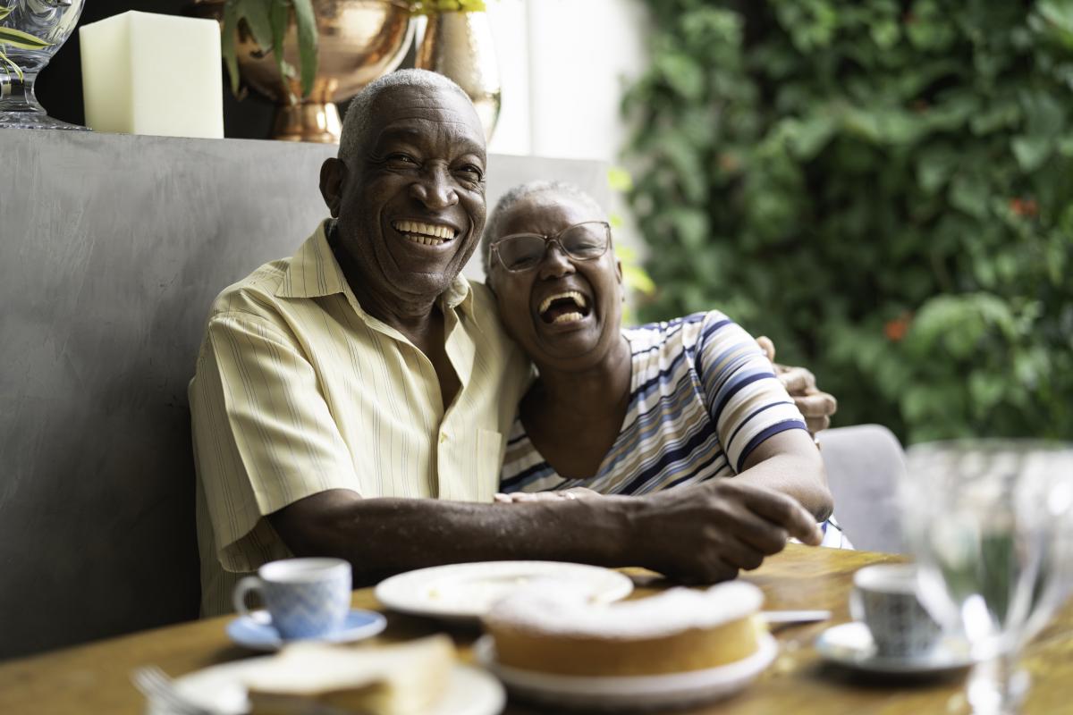 Elderly couple sitting down, embracing and smiling
