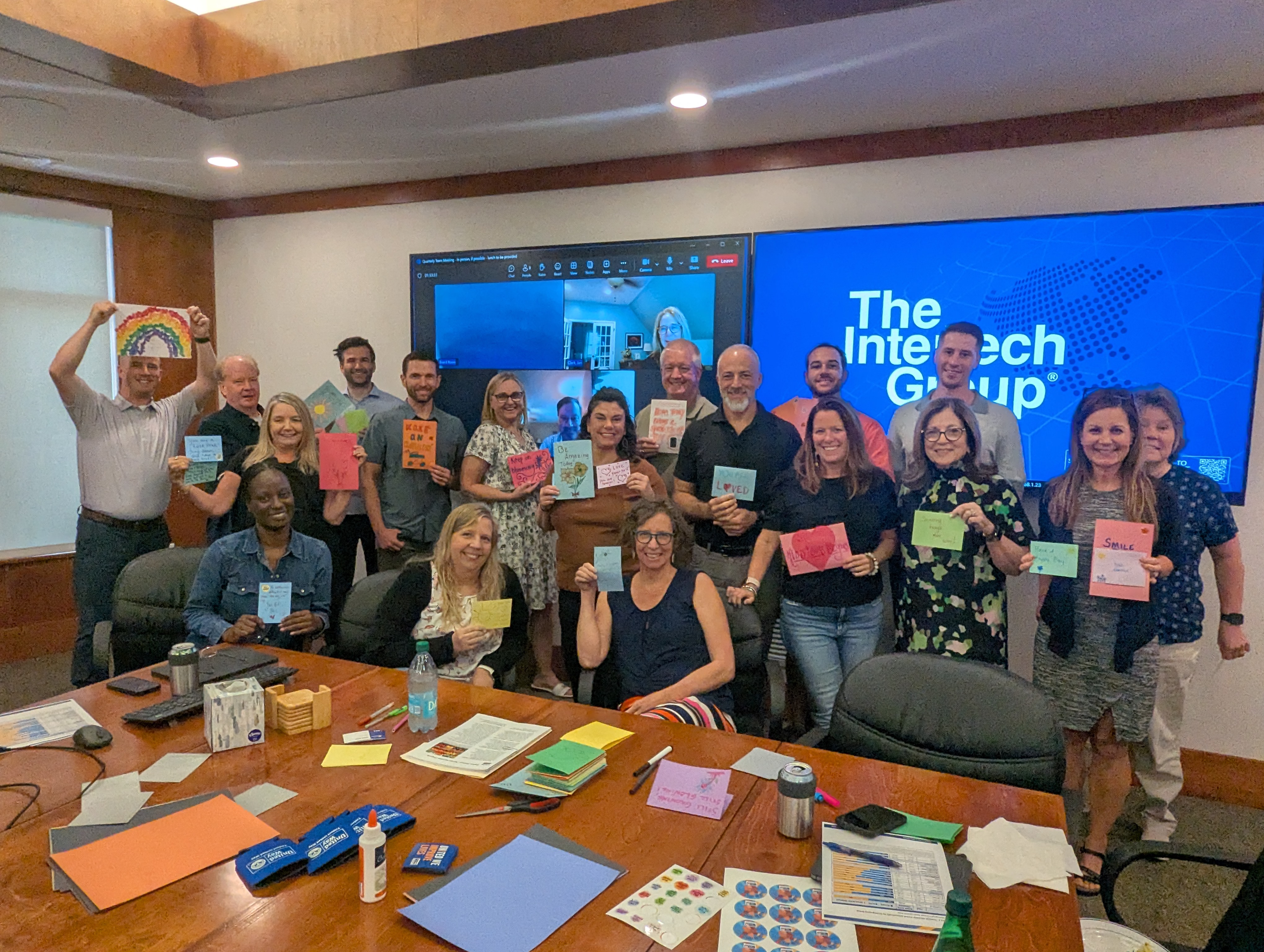 A group of employees from The Intertech Group pose with cards of encouragement they made during a workplace volunteering event.