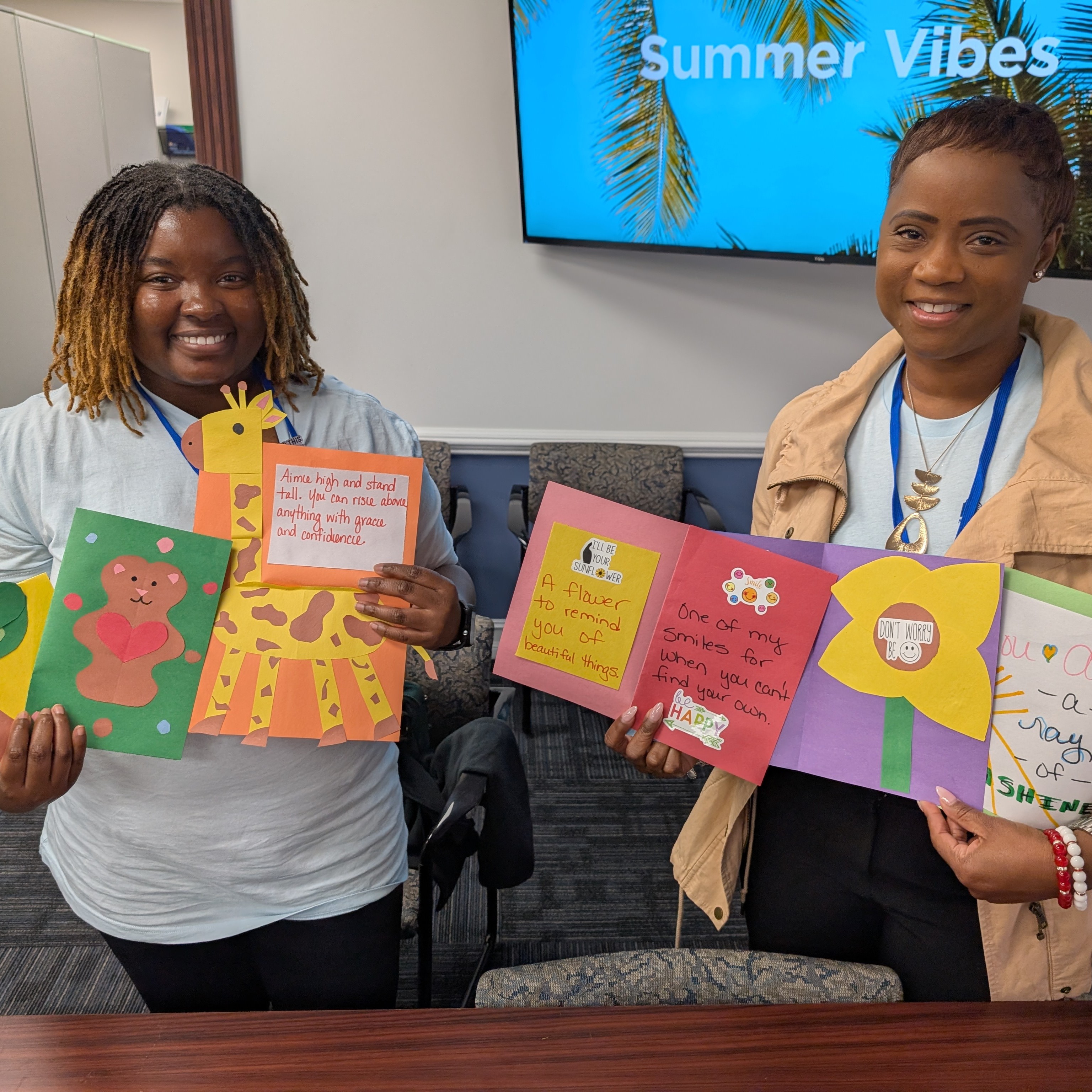2 volunteers pose with notes of encouragement.