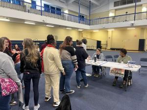 A line of people waiting to speak with a woman sitting behind a table