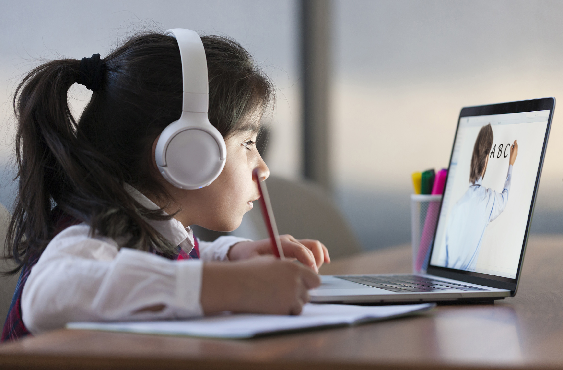 girl with headphones doing homework on computer