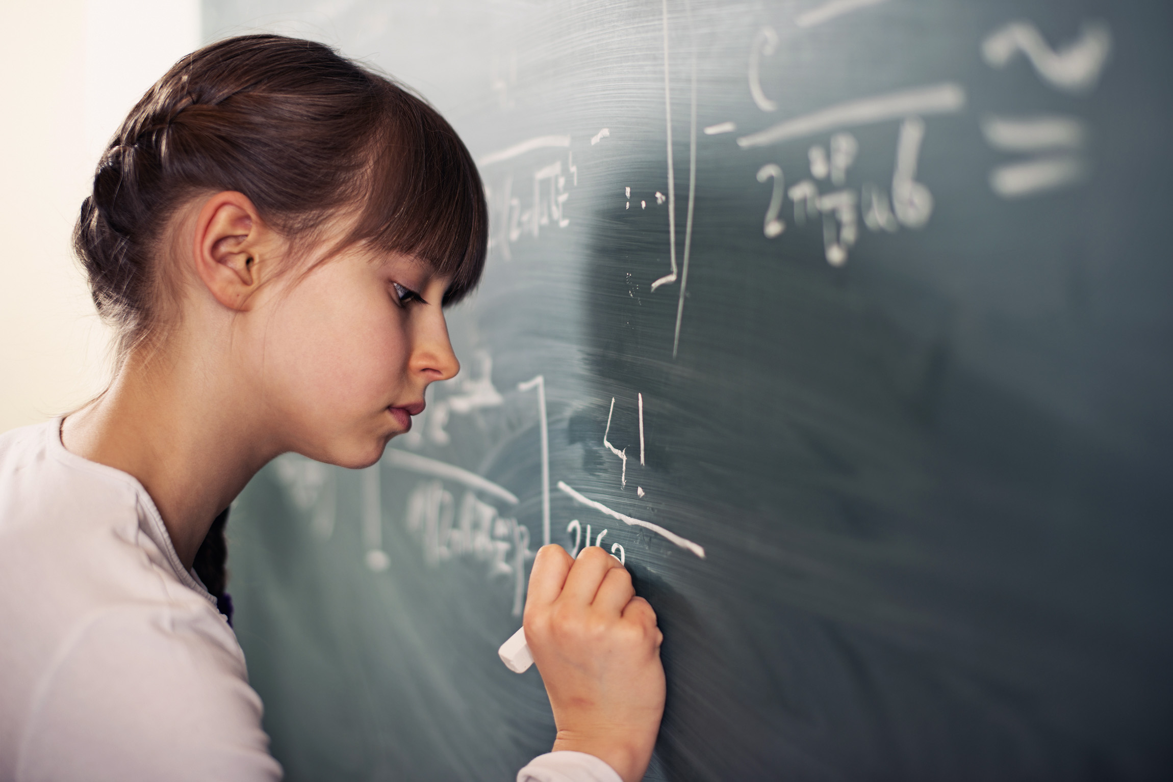 girl writing equations on chalkboard