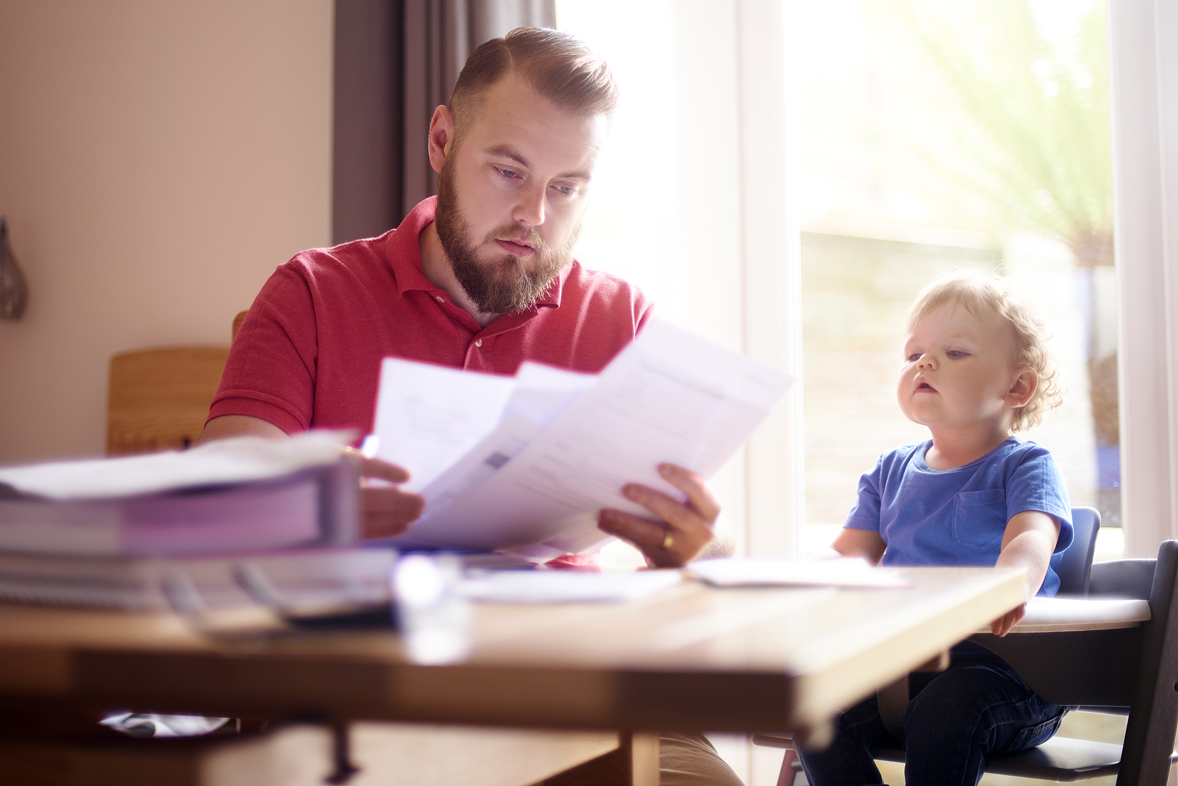 man sitting with kid looking at bills