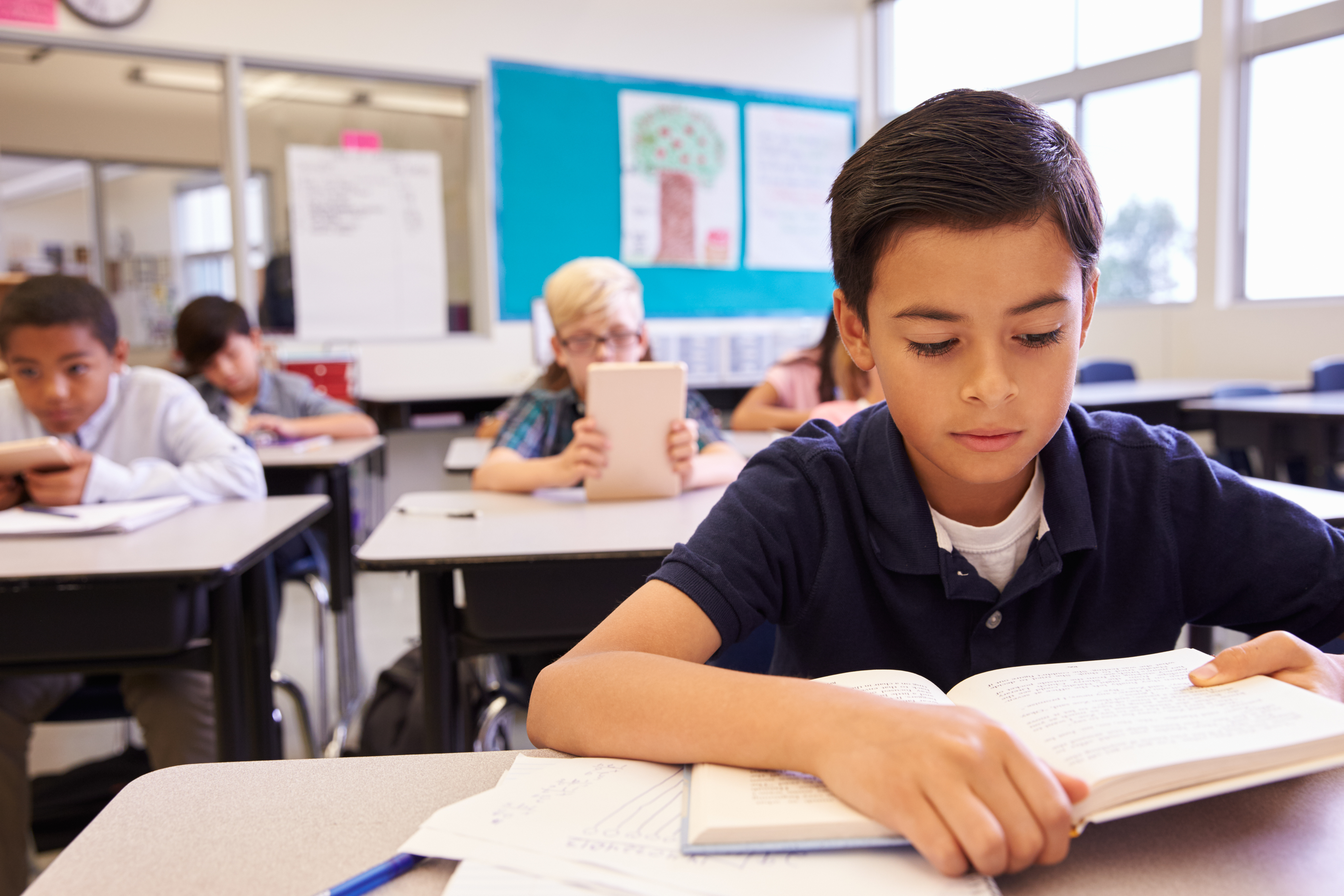 child reading book in classroom