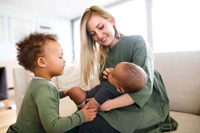 Woman holding baby and toddler looking on