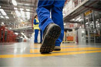 close-up on a person wearing a pair of boots and walking in a warehouse setting