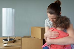 Sad mother embracing young child next to packed moving boxes