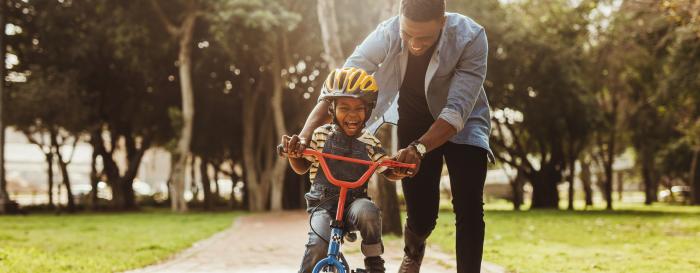 Man helping a young boy learn how to ride a bike