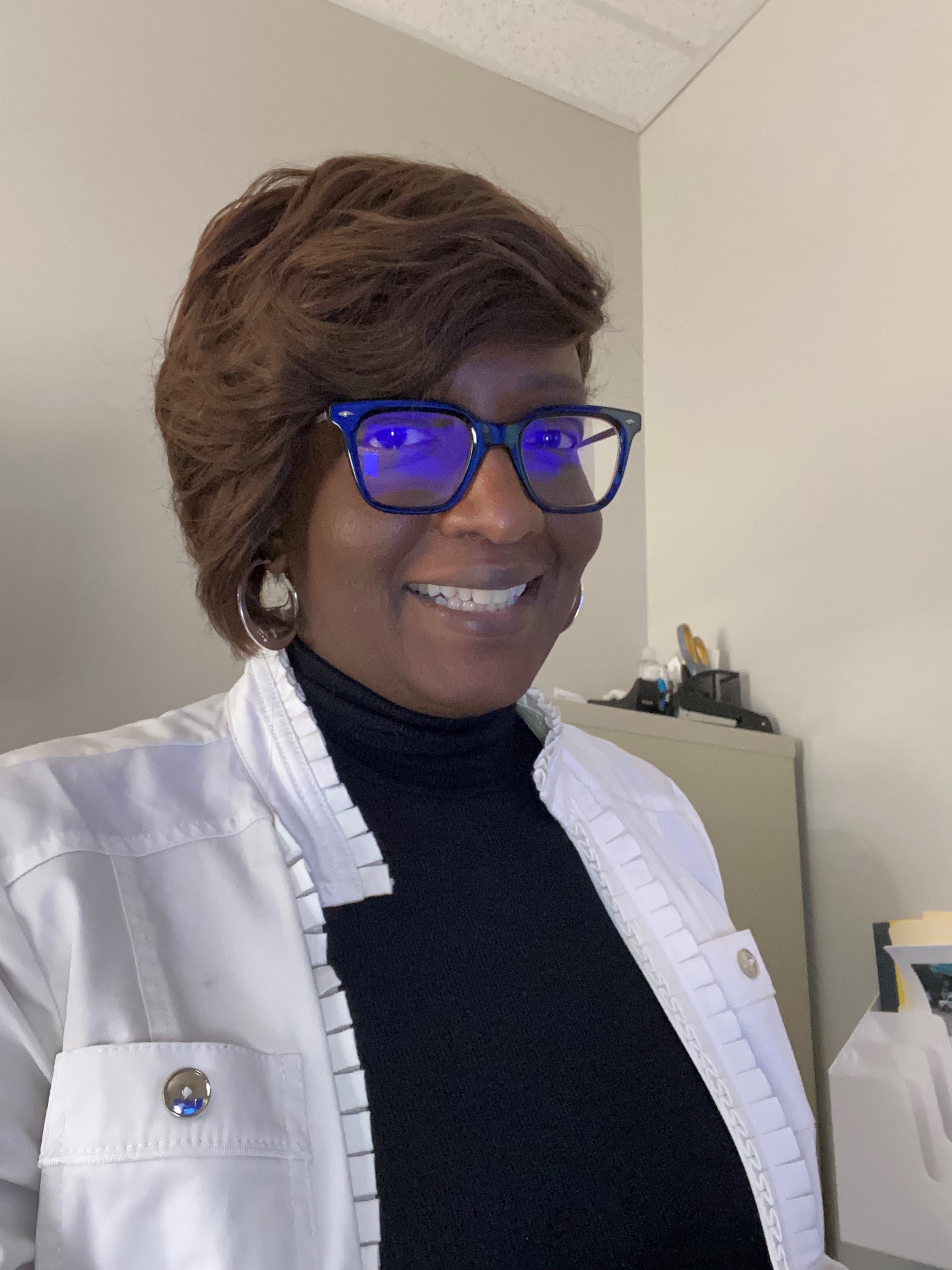 Headshot photo of Tasha Singleton, Skills-Based Volunteer, wearing glasses, a white jacket and black shirt