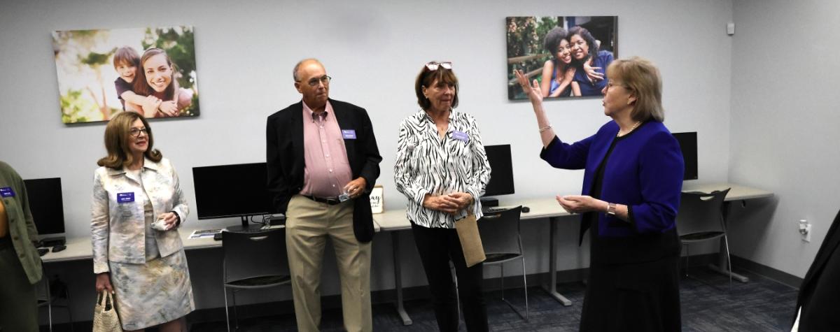 Photo from a tour, Anita Zucker and Bruce and Diane Hoffman are looking at Cathy Easley as she talks about the Center for Strong Families.