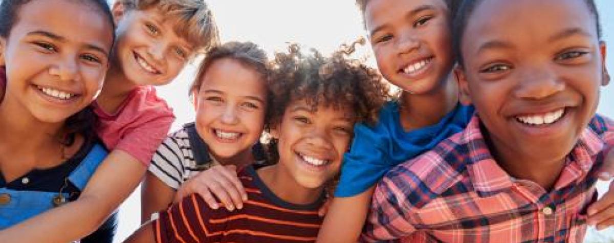 A group of kids outside, goofing off and smiling at the camera