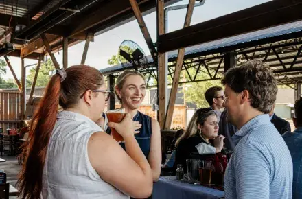 Photo of a group of three people talking at the last YLU Happy Hour. One of the girls is smiling and mid-conversation.